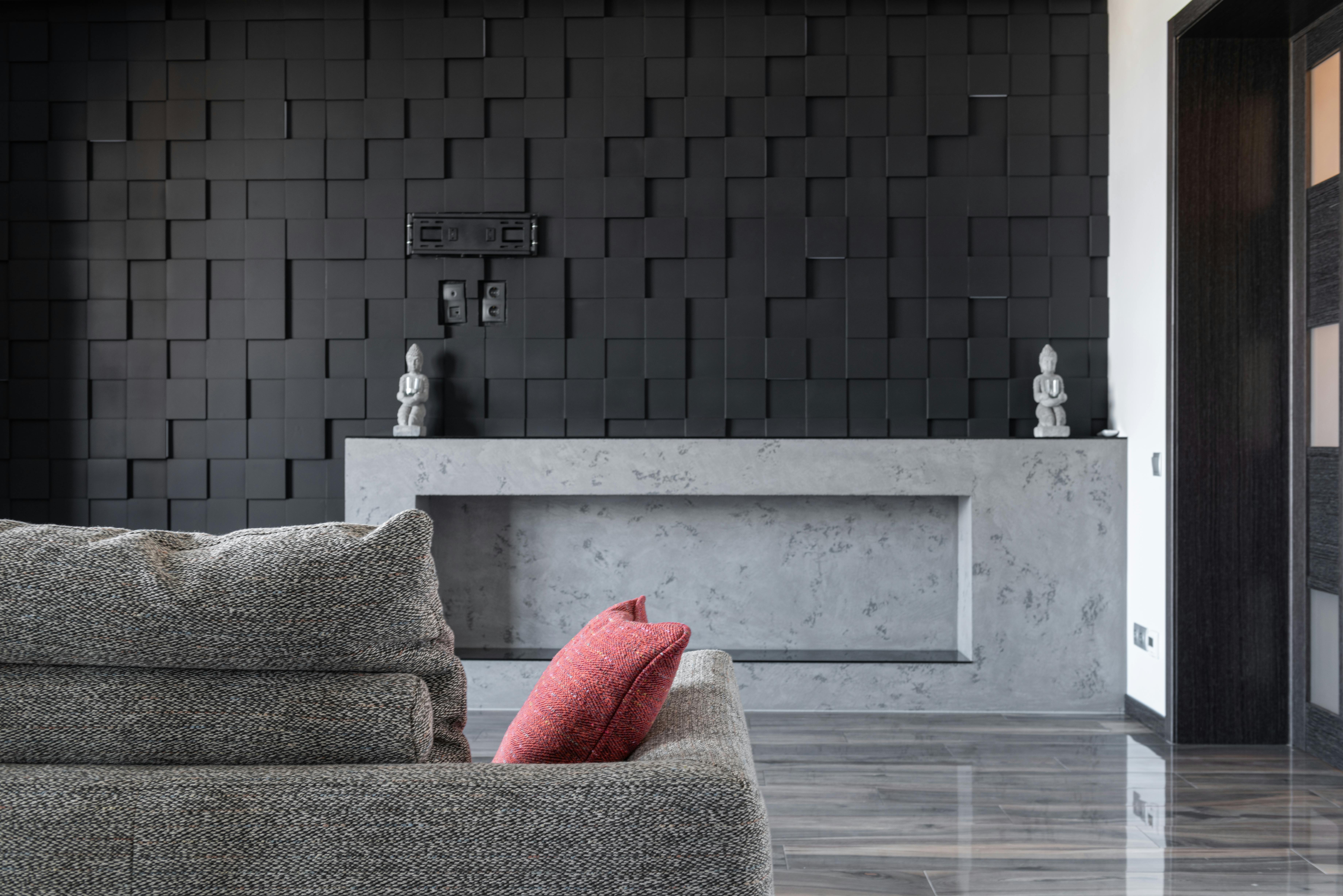 Wohnzimmer mit grauer Betonoptik-Akzentwand, Holzdetails und warmem Licht