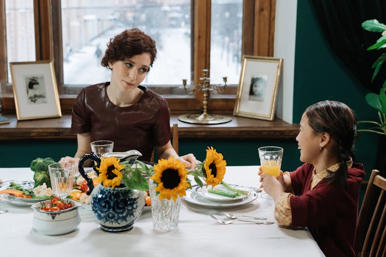 A Woman Having Refreshments With A Child On A Dining Table
