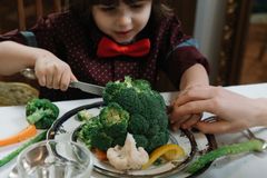 Young boy with bowtie delightfully eating a meal of fresh vegetables, emphasizing wholesome childhood dining.