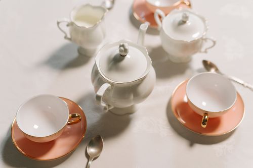 Free A vintage porcelain tea set featuring teapot, cups, saucers, and sugar bowl on a white surface. Stock Photo