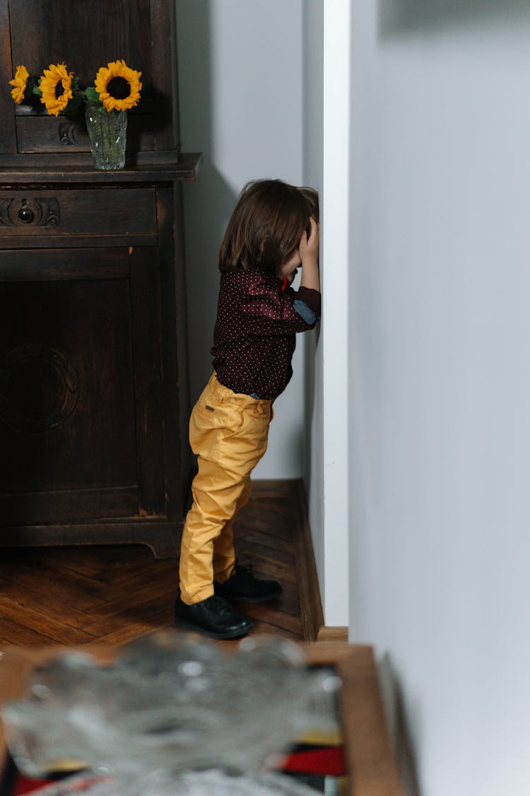 A Boy Standing Facing The Wall 