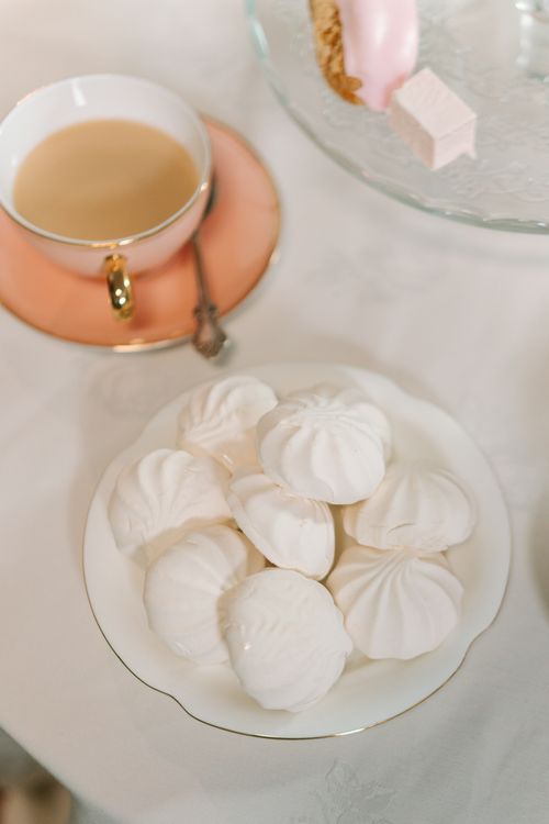 Free Cozy table scene with meringues and tea cup on porcelain plates. Soft lighting accentuates the elegant setting. Stock Photo