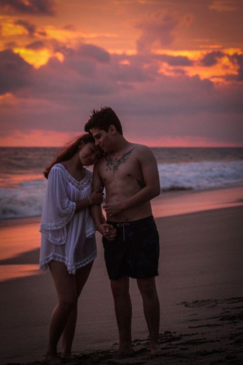 Free A romantic couple embracing on a beach during a beautiful sunset. Stock Photo