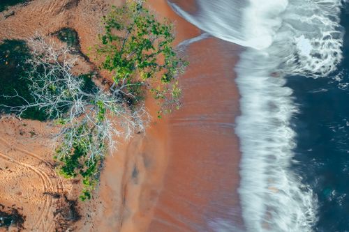 Free Drone view long exposure of foamy waves of blue clear ocean rolling on wet sandy beach Stock Photo
