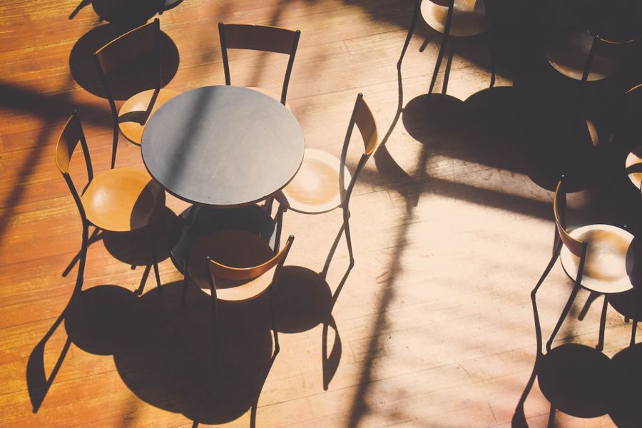 Late sun throwing long chair shadows across a wooden café floor