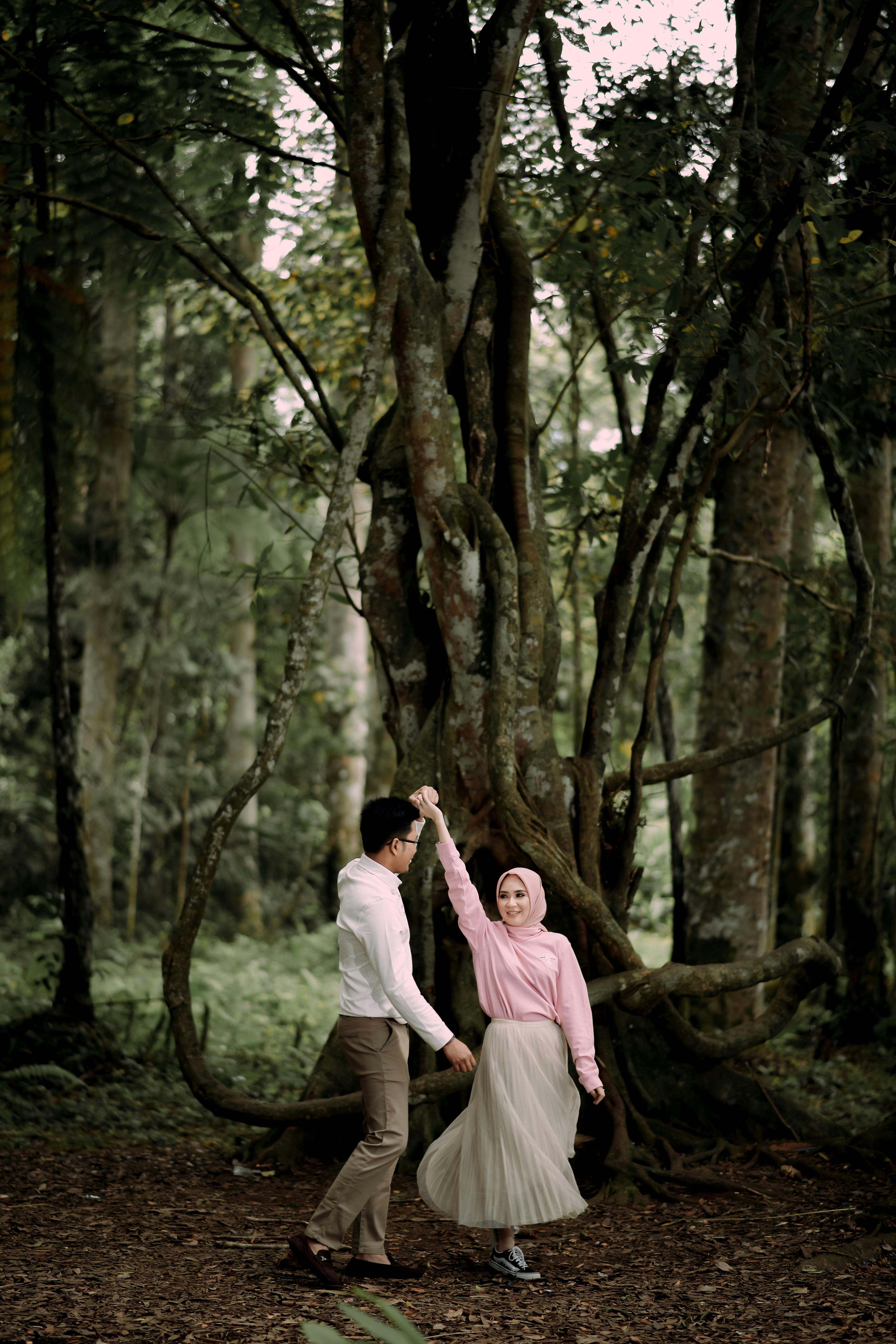 Joyful moment of a couple dancing in a lush forest, showcasing connection and happiness.