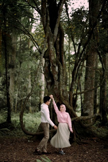 Joyful moment of a couple dancing in a lush forest, showcasing connection and happiness.