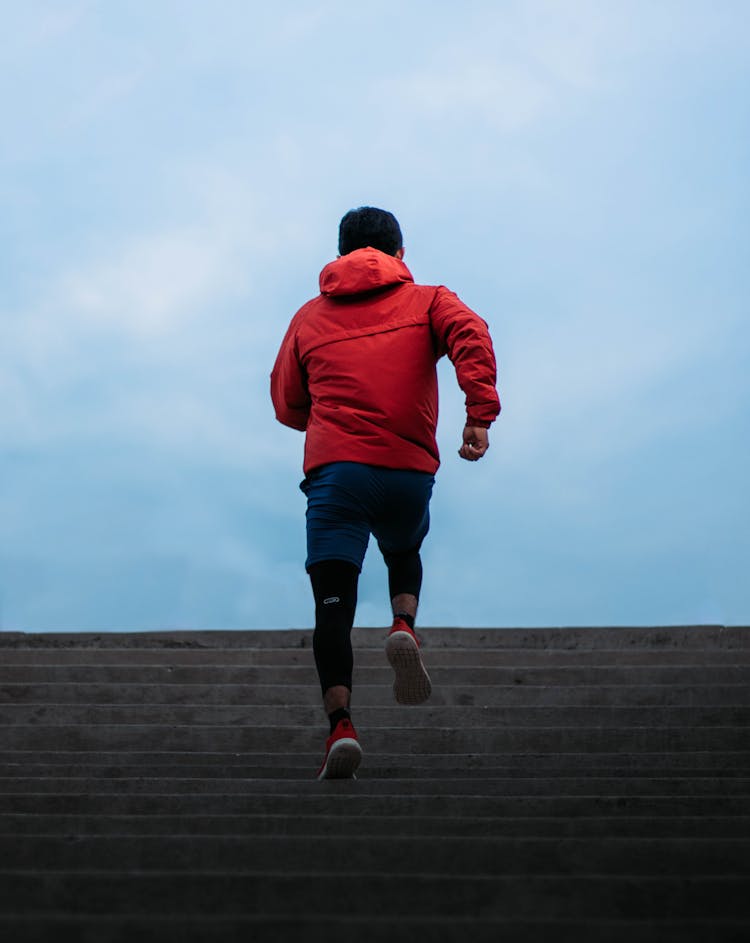 Man In Red Hooded Jacket Running On Concrete Stairs