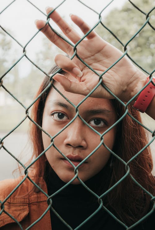 Woman Behind the Green Chain Link Fence