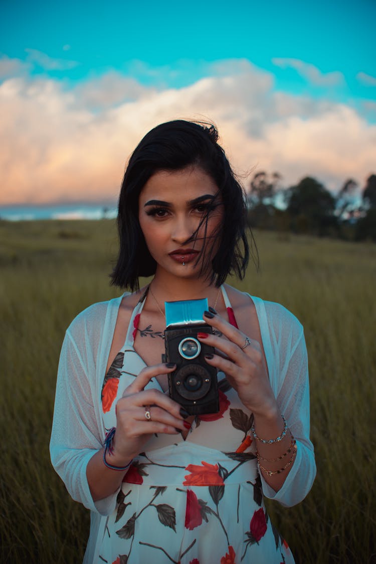 Ethnic Woman With Retro Camera In Field