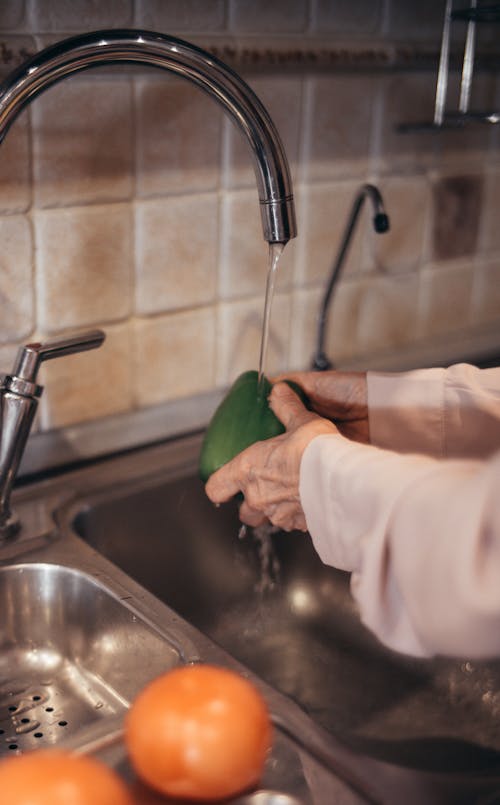 Free Person Washing a Green Bell Pepper Stock Photo