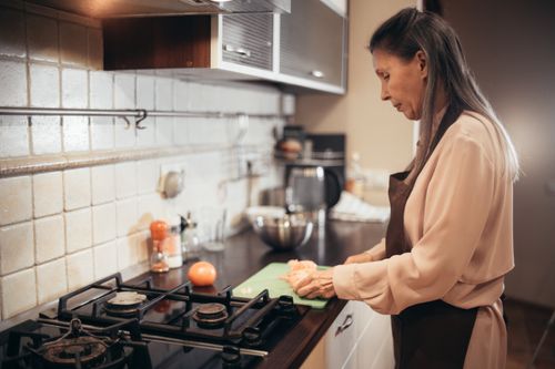 Free Caucasian woman slicing food in an inviting home kitchen setting. Stock Photo