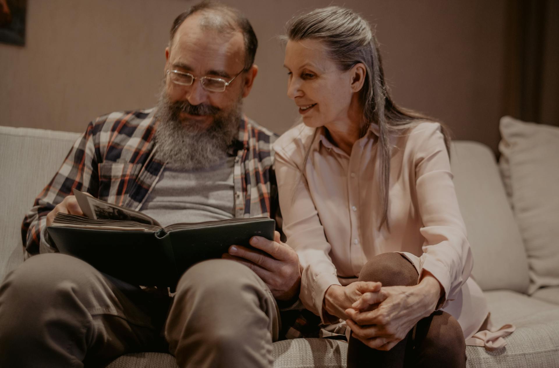 A Couple Sitting on the Couch Looking at the Photo Album