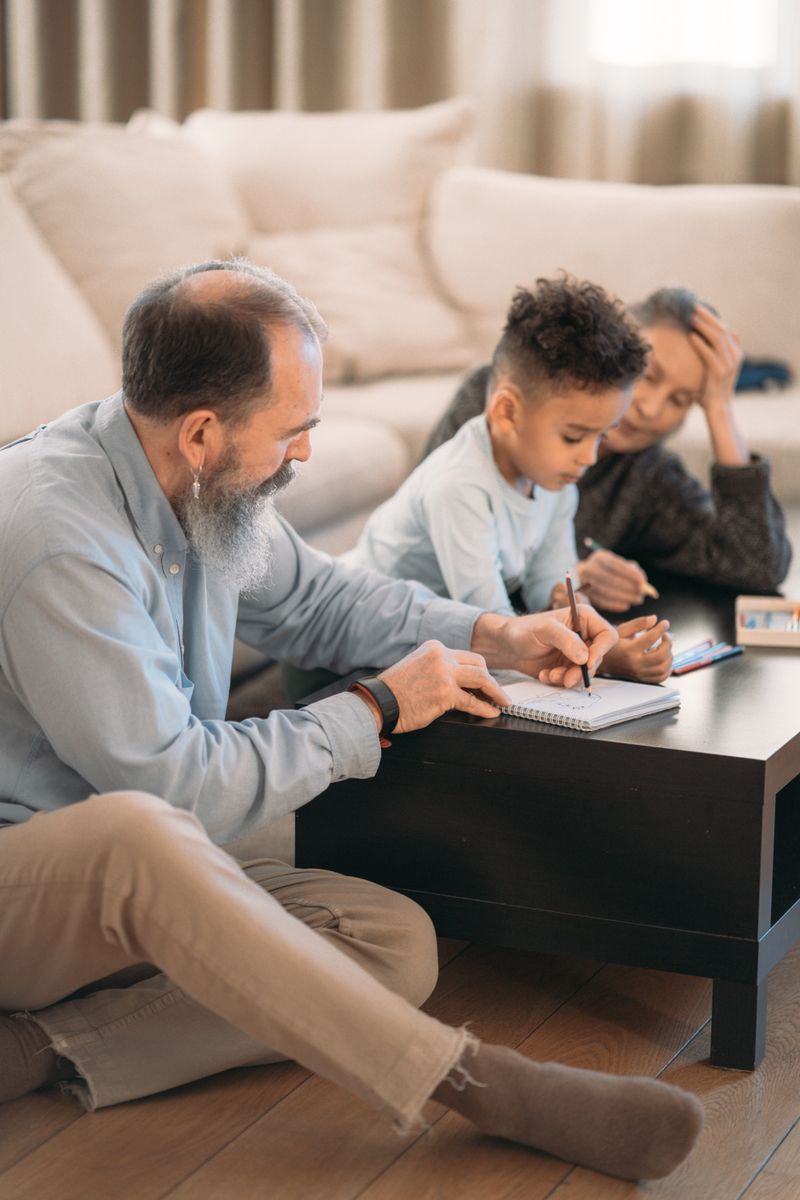 Elderly couple teaching young grandson at home, creating a heartwarming family moment.