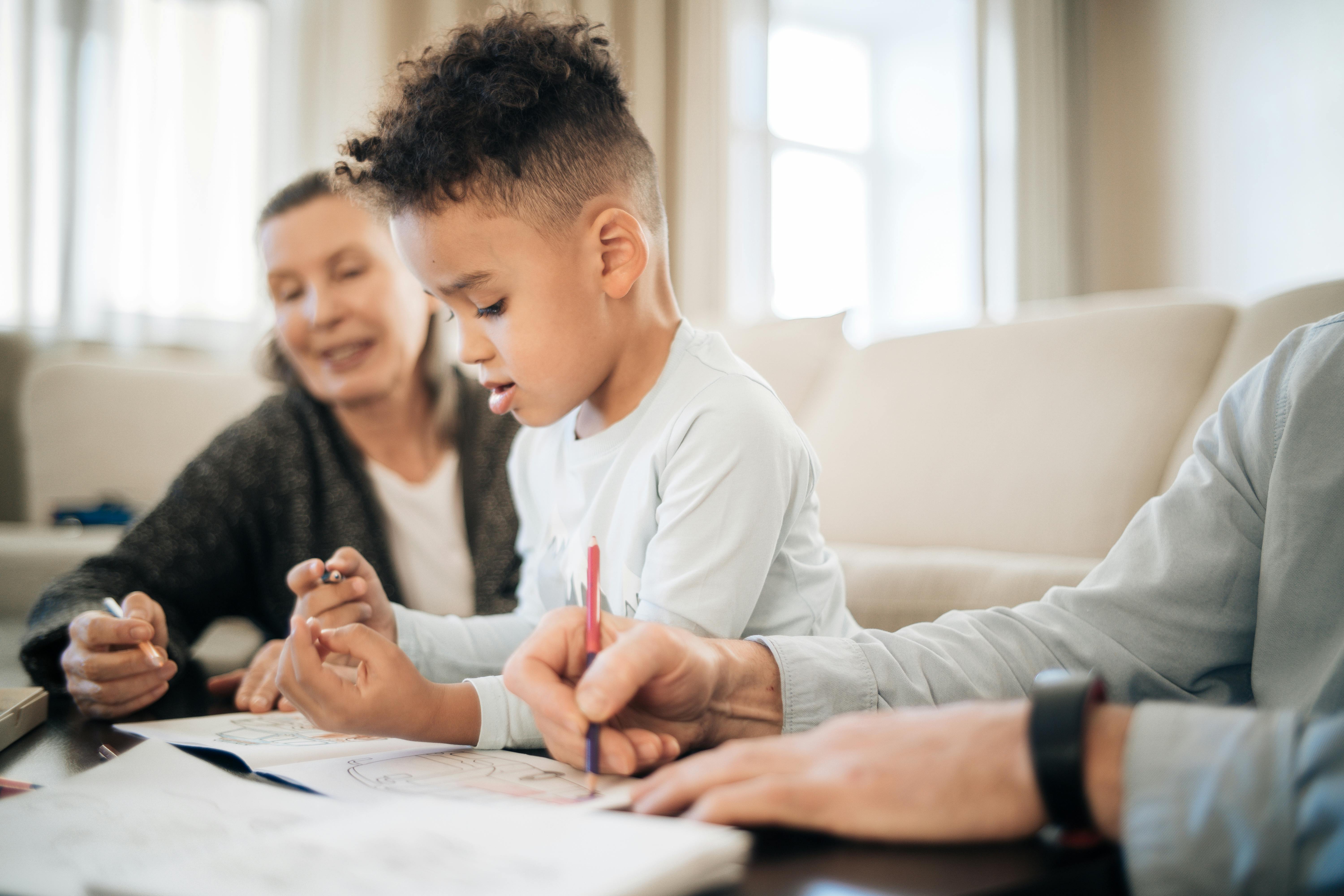 multiethnic kid with grandparents drawing on paper at table