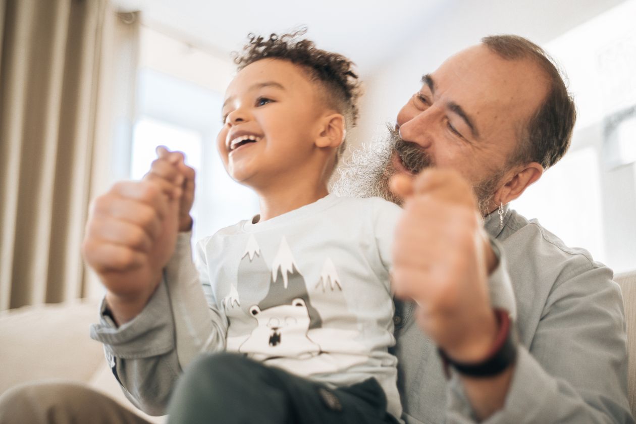 A happy kid sitting on his grandfather's lap