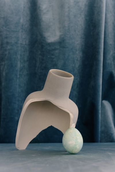 Hand-thrown stoneware vessel resting against a slate-blue drape — photo by Ksenia Chernaya on Pexels