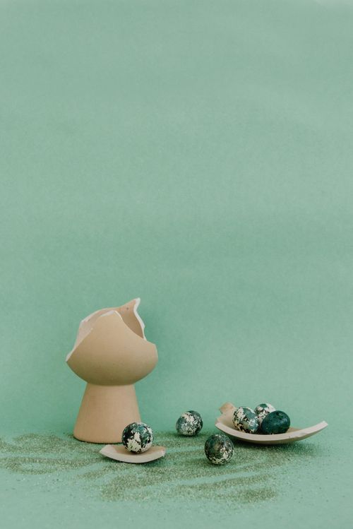 Free A creative still life display of cracked eggshells and marble eggs on a teal background. Stock Photo