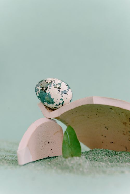 Free A unique abstract arrangement featuring a speckled egg and ceramic pieces on a textured surface. Stock Photo