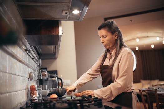 Elderly woman prepares food in a warm, cozy kitchen environment. Home cooking vibe.