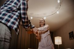A happy senior couple dancing joyfully indoors, embracing a moment of togetherness.