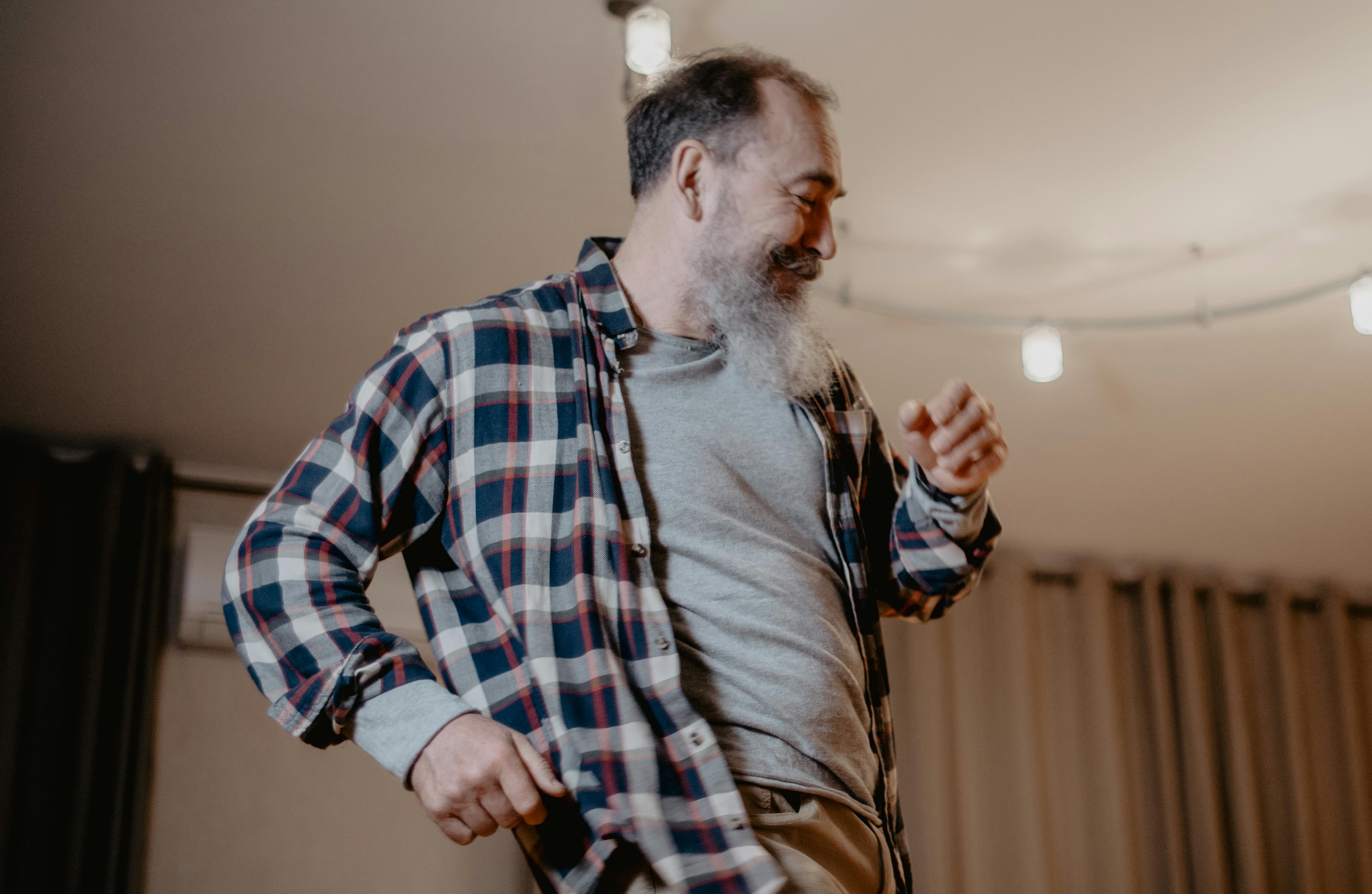 Senior man joyfully dancing indoors, showing happiness and vitality.