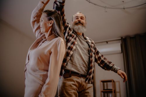 Free An elderly couple enjoying a dance together in their cozy living room, showcasing love and companionship. Stock Photo