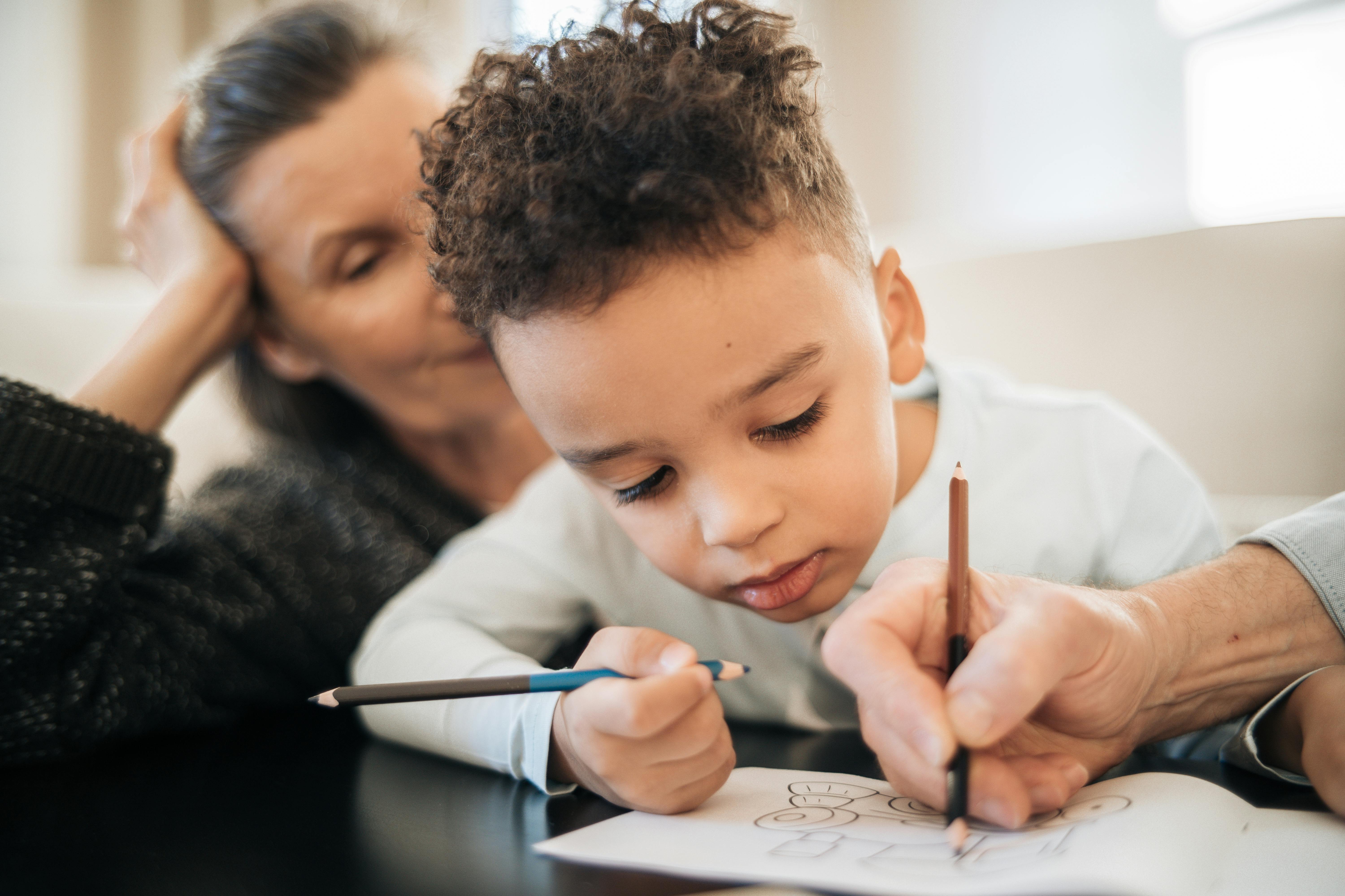 boy in black shirt writing on white paper