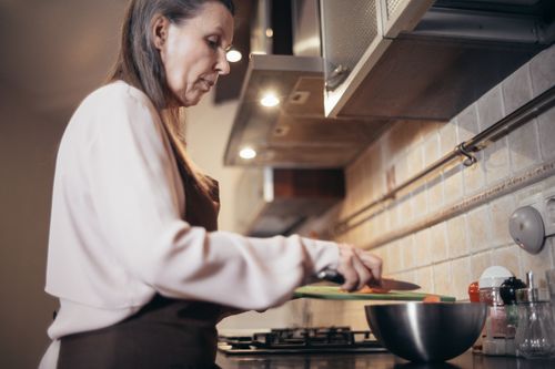Free Senior woman preparing a meal in a modern home kitchen, focusing on healthy cooking. Stock Photo