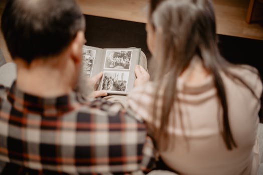 A couple reminisces while looking through a family photo album, capturing warm memories indoors.