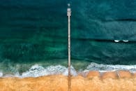 令人惊叹的鸟瞰图中，一座孤零零的码头伸向深蓝色的海洋，充满活力的海浪不断涌上岸边