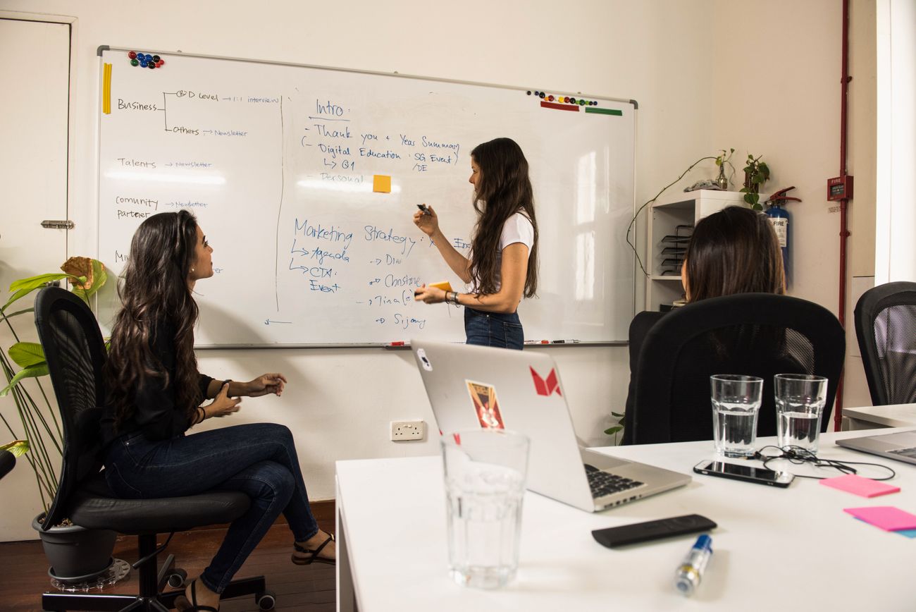 Twee professionals bespreken de strategie aan een whiteboard