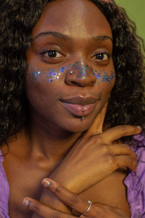 Trendy black woman with glitters on face