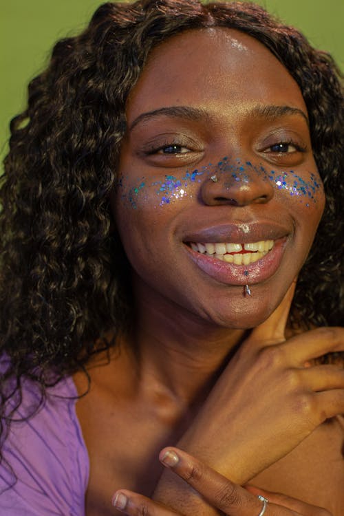 Black woman with glitter on face and curly hair