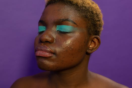 Crop calm extraordinary African American female with eyes closed and green eyeshadows on purple background