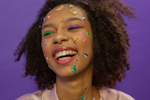 Cheerful black woman with dinosaur stickers on face
