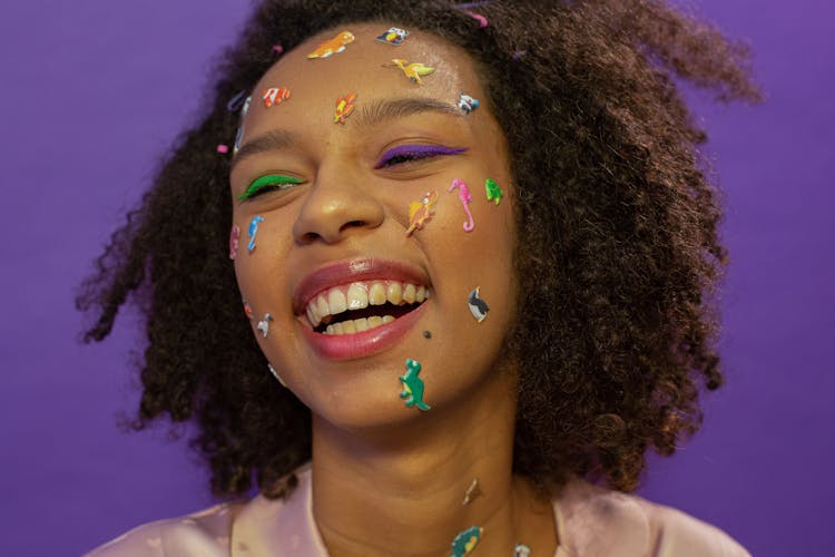 Cheerful Black Woman With Dinosaur Stickers On Face