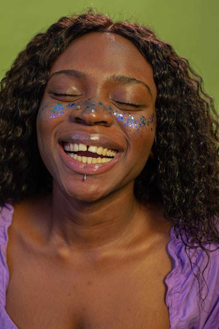 Portrait Of Smiling Woman With Glitter On Face And Piercing In Lip