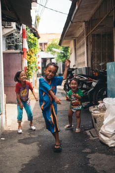 Three happy children playing in a vibrant urban alley, enjoying a sunny day.