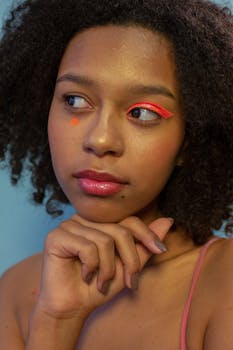 Close-up of a woman with striking eye makeup and thoughtful expression.