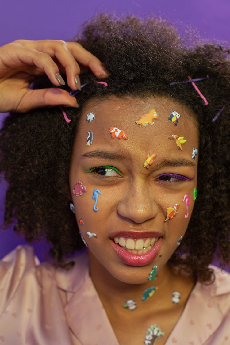 Unhappy Black Teenager With Animal Stickers On Face And Bobby Pins