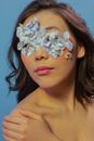 Serious female with blue flower petals on face
