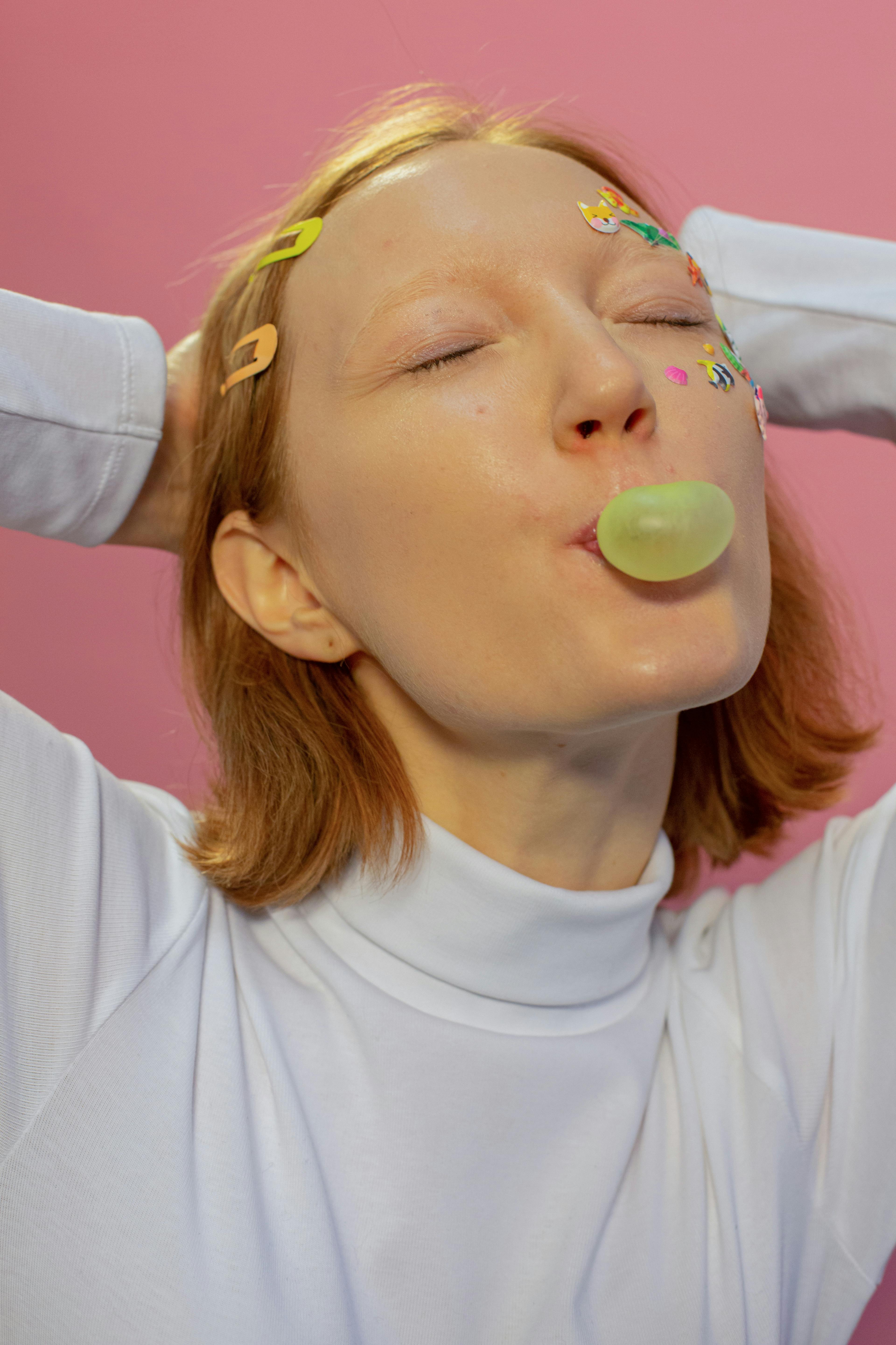female blowing bubble with gum with stickers on face