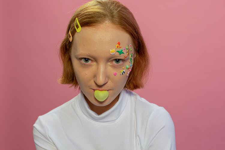 Lady With Animal Stickers On Face Blowing Bubble With Gum