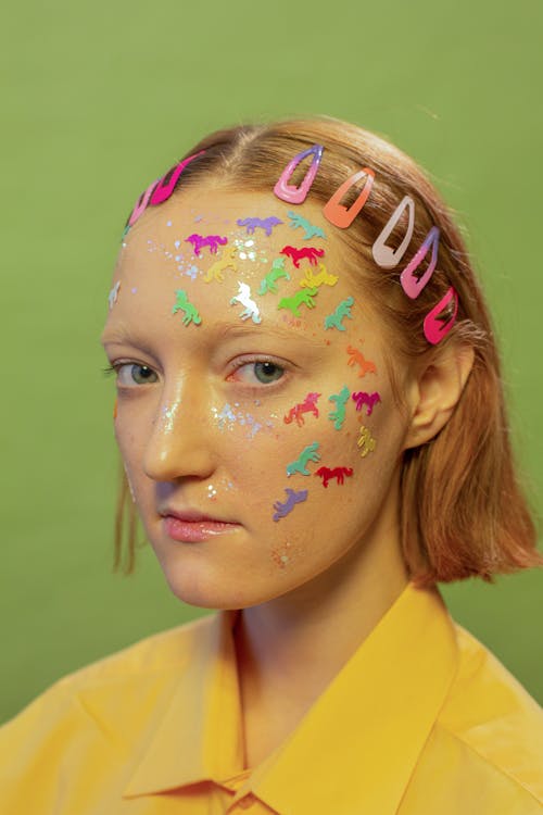 Free Lady with unicorn stickers and glitter on face in studio Stock Photo