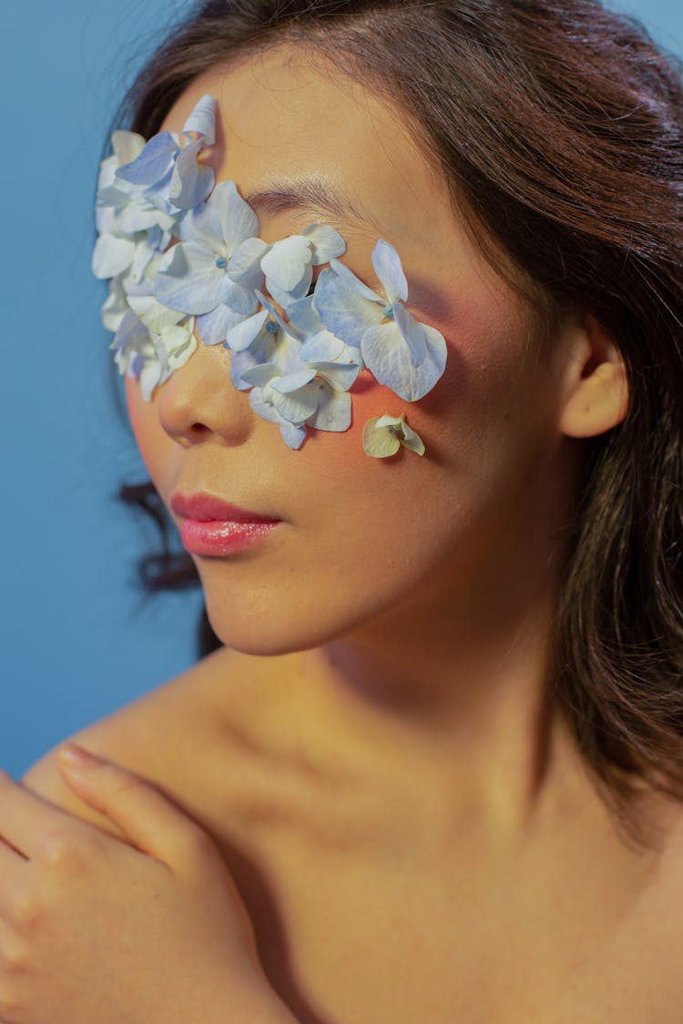 Thoughtful Lady With Flower Petals On Face In Studio