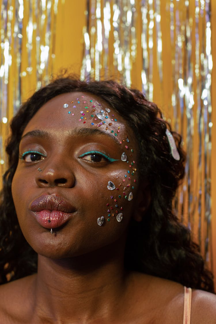 Black Woman Blowing Kiss With Piercing And Rhinestones Near Tinsel