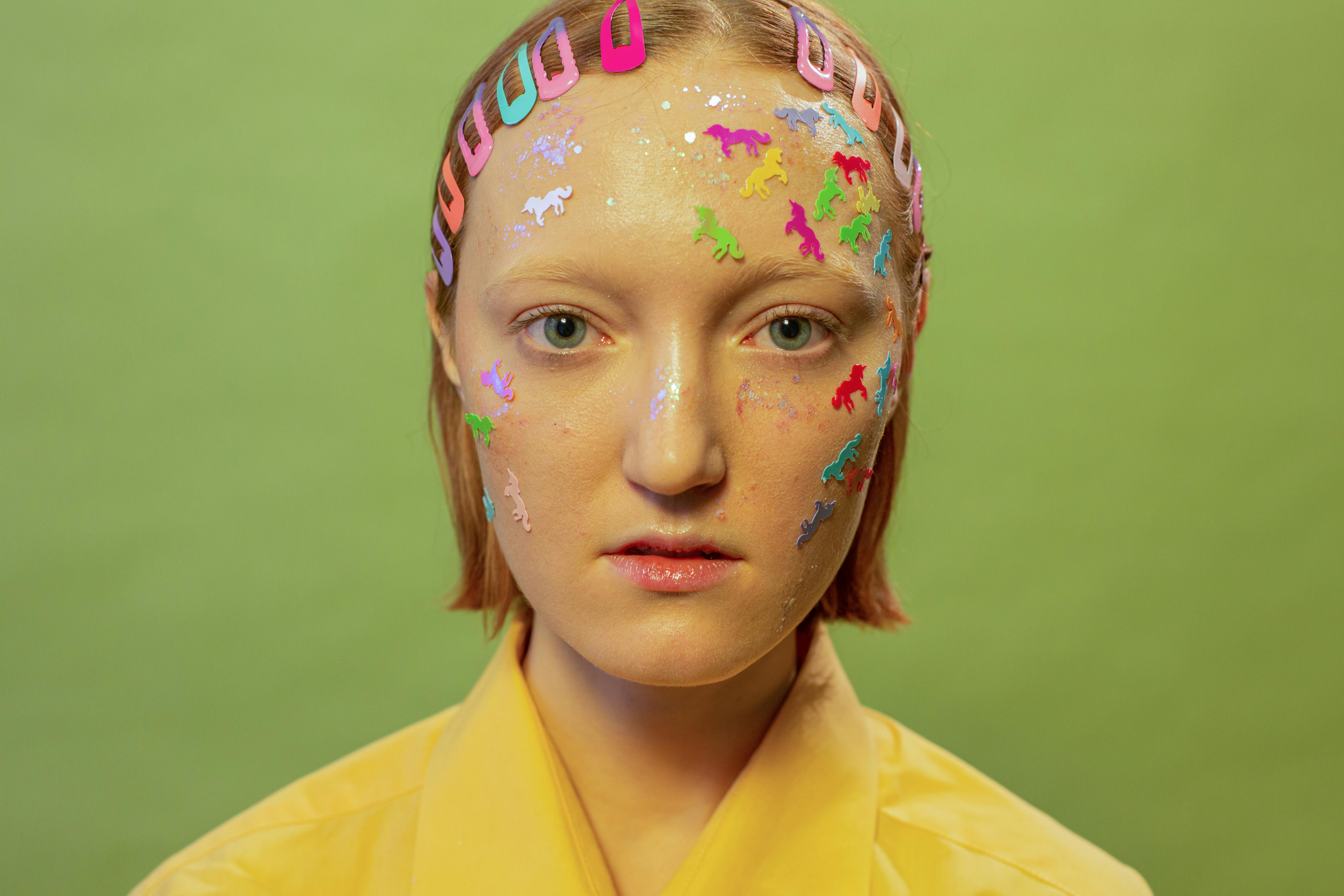 female with stickers and glitter on face with hairpins