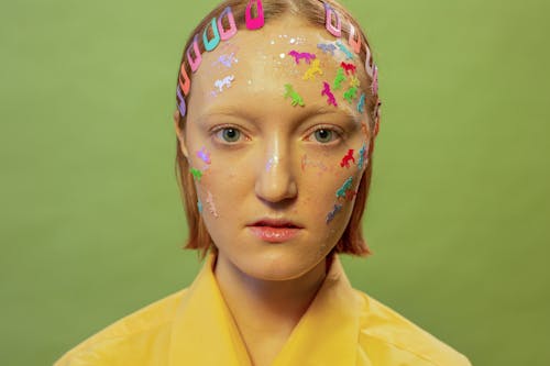 Female with stickers and glitter on face with hairpins