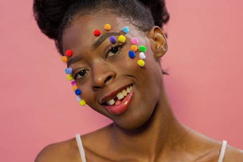 Smiling black female with colorful fluffy small balls on face